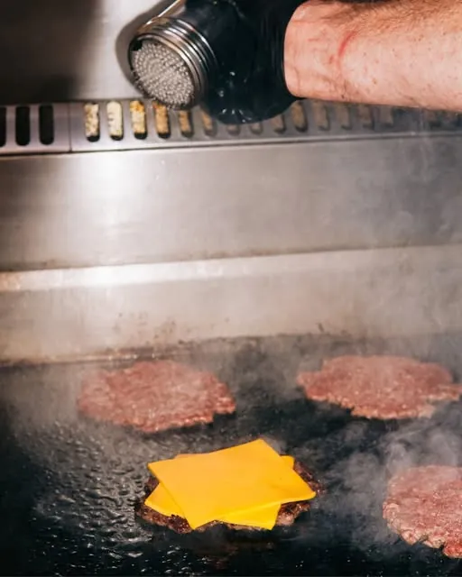 Seasoning smash patties on the flat-top grill